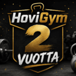 HoviGym 2 vuotta – tumma ja blurattu kuntosali tausta sekä kynttilällä varustettu kakkonen cupcake päällä