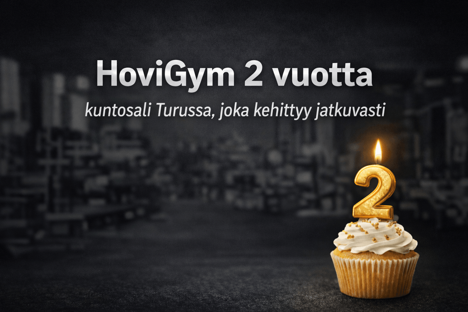HoviGym 2 vuotta – tumma ja blurattu kuntosali tausta sekä kynttilällä varustettu kakkonen cupcake päällä
